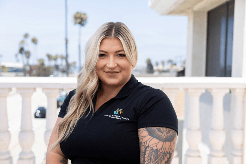 Laci James, Mental Health Center of San Diego staff member. Portrait of woman with blonde hair and tattoos.